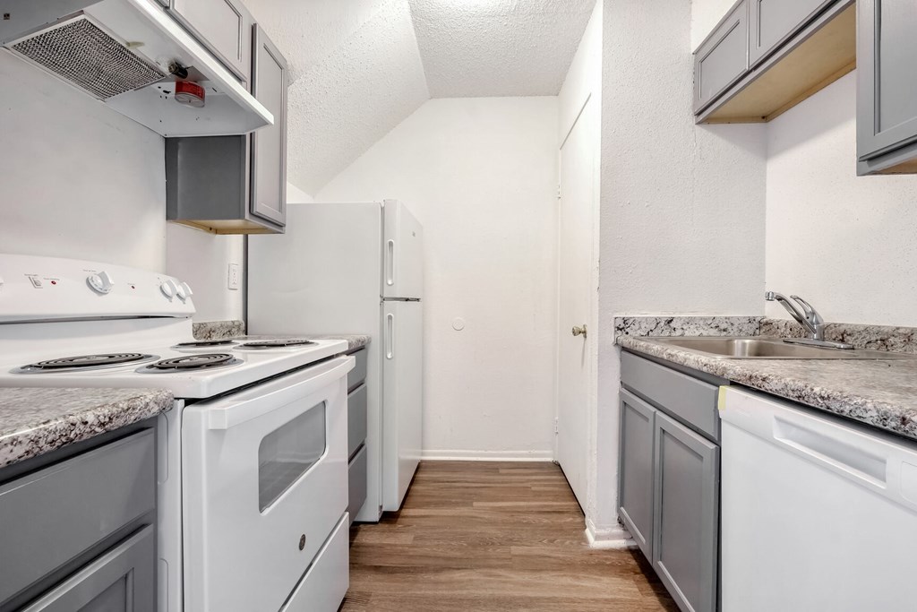 A kitchen with white appliances and a marble countertop.
