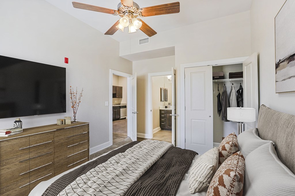 A living room with a brown and white patterned rug, a white couch, and a wooden ceiling fan.