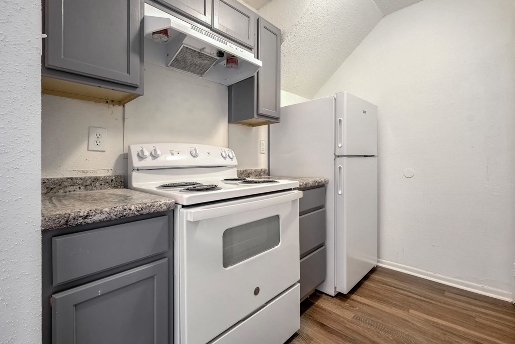 A kitchen with a white stove and grey cabinets.