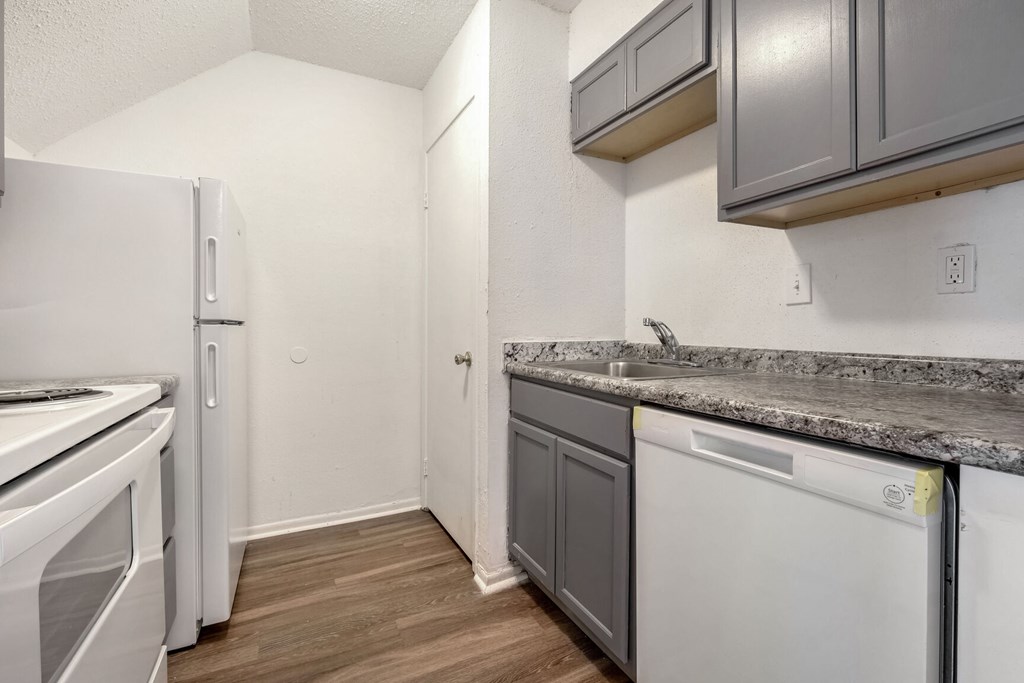 A kitchen with a white fridge, a white dishwasher and a white oven.