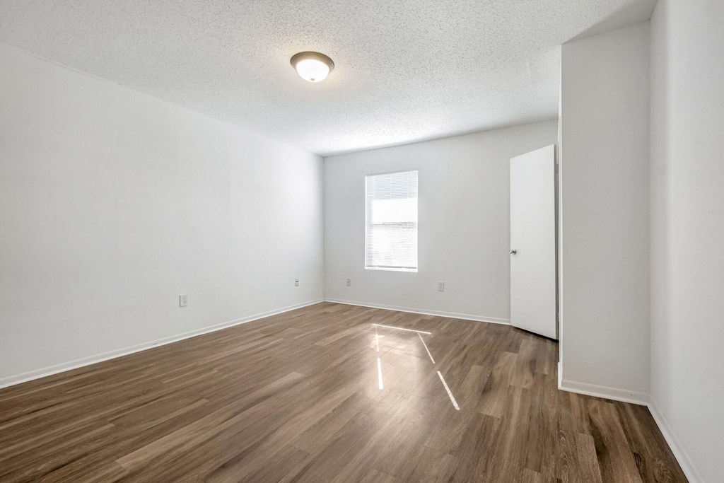 A room with wooden flooring and a window.