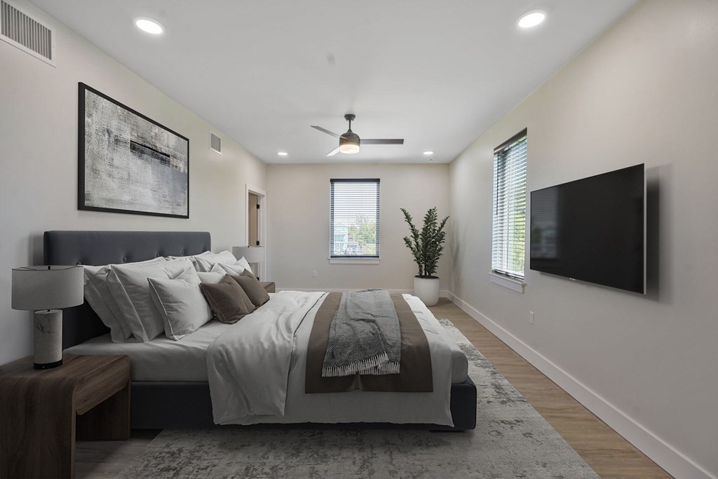 A bedroom with a large bed and a flat screen TV mounted on the wall.
