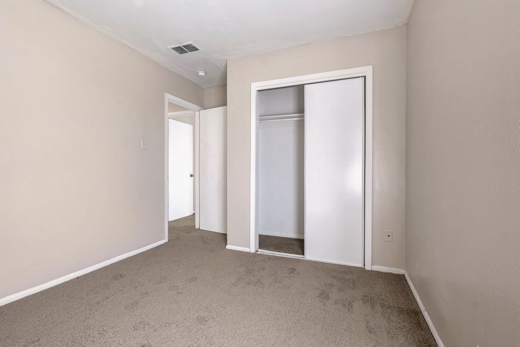 A room with a white door and a carpeted floor.