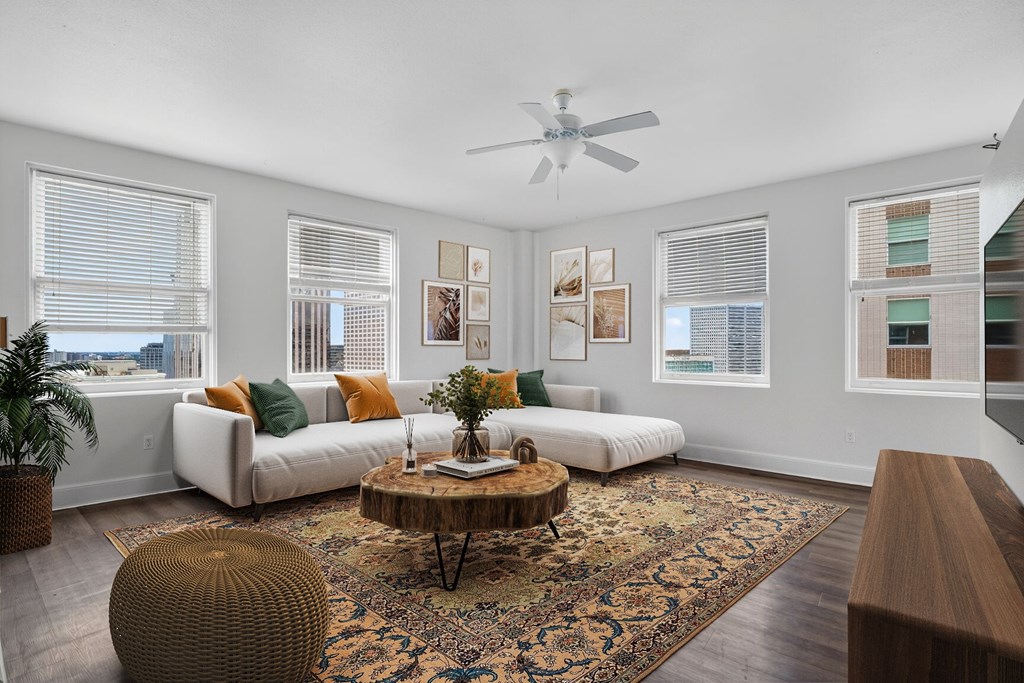 A living room with a white couch, a brown ottoman, and a rug.