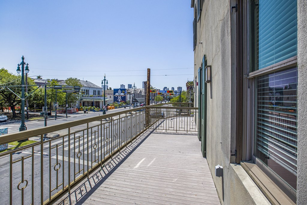 A wooden walkway with a metal railing runs down the side of a building.