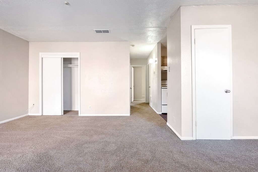 A spacious room with carpeted floor and white walls.