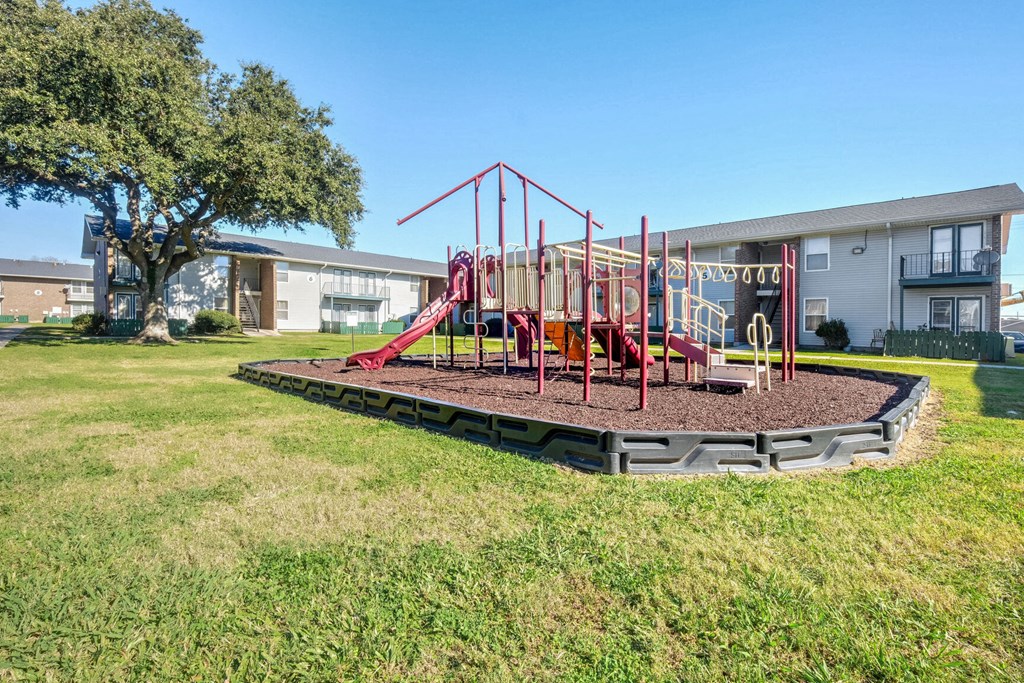 A playground with a red swing set and a slide.