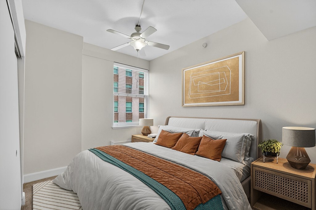 A bedroom with a bed, nightstand, and a ceiling fan.