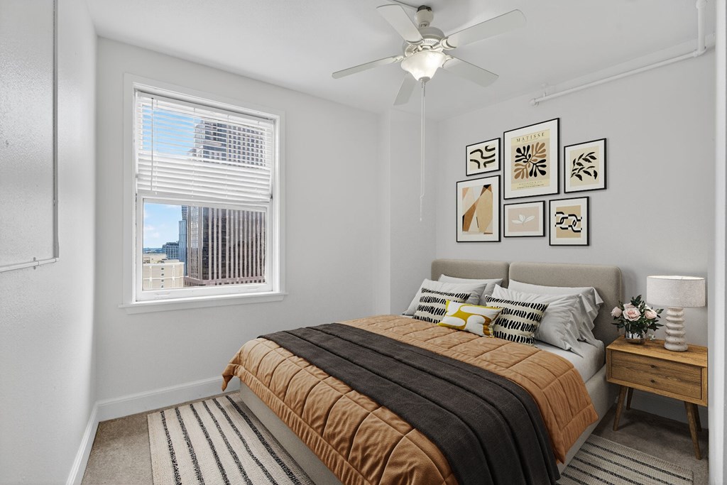 A bedroom with a bed, a ceiling fan, and pictures on the wall.
