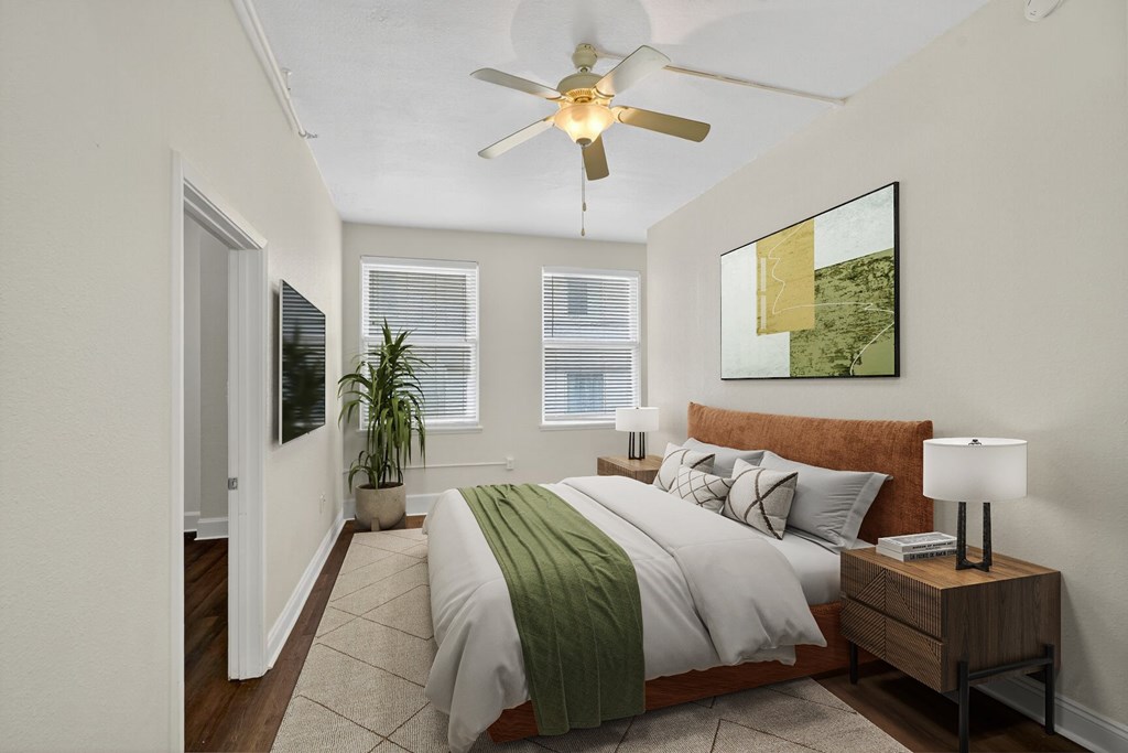 A bedroom with a bed, a ceiling fan, and a painting on the wall.