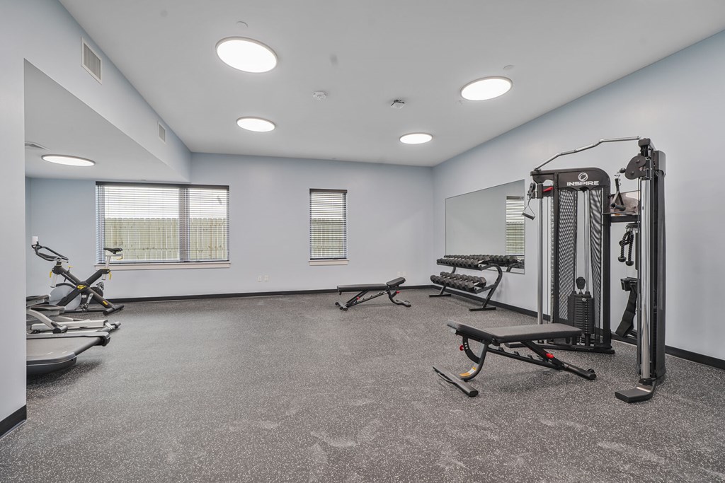 A spacious gym with a variety of equipment including treadmills, elliptical machines, and weight machines.