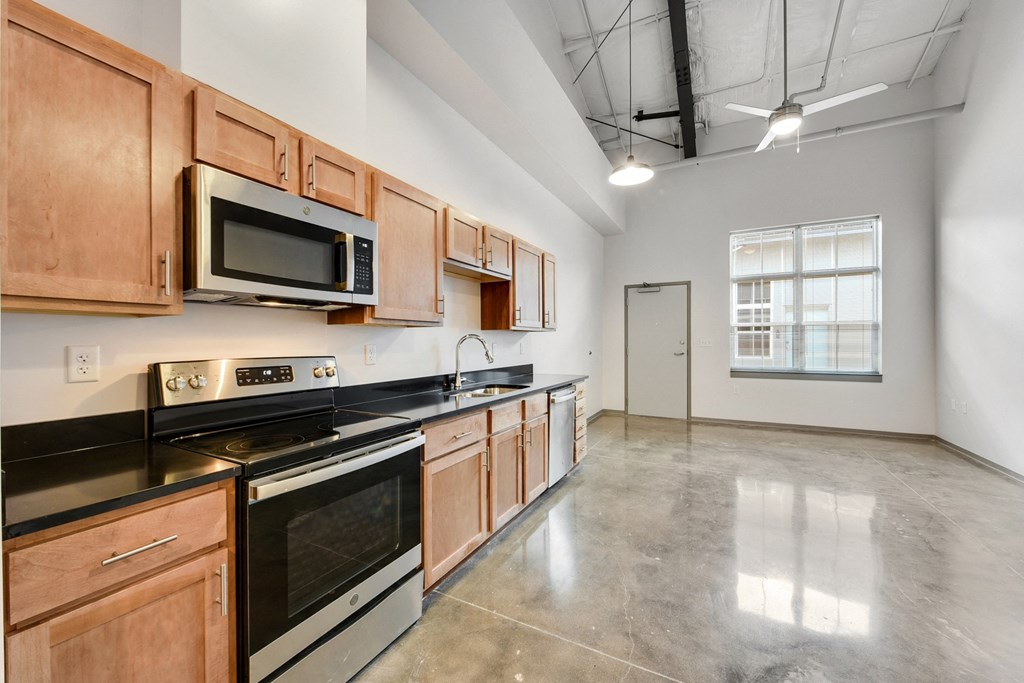 an empty kitchen with wood cabinets and black counter tops and stainless steel appliances