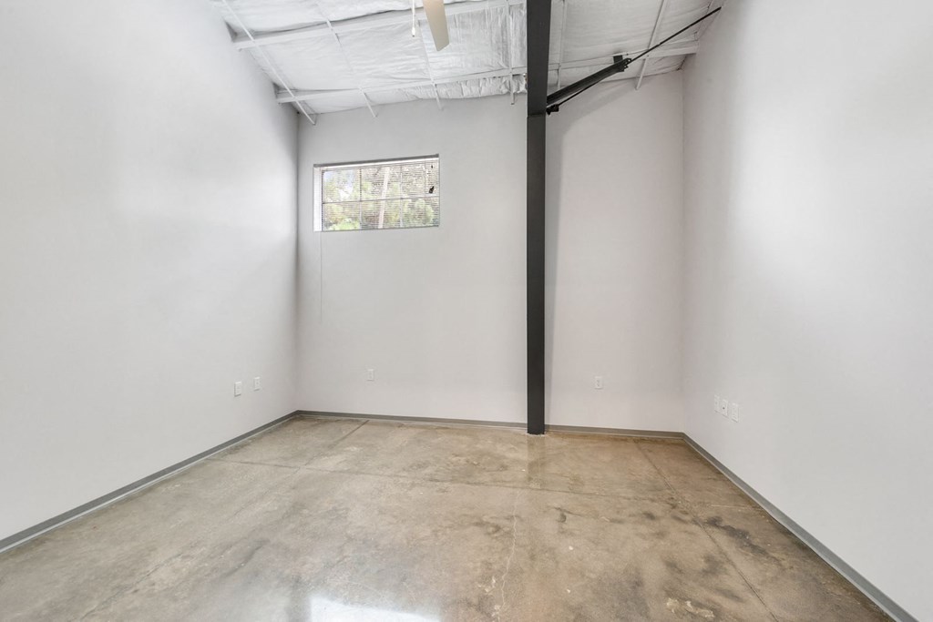 a room with white walls and a window and a cement floor