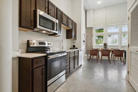 a kitchen with wooden cabinets and stainless steel appliances and a dining room with a window