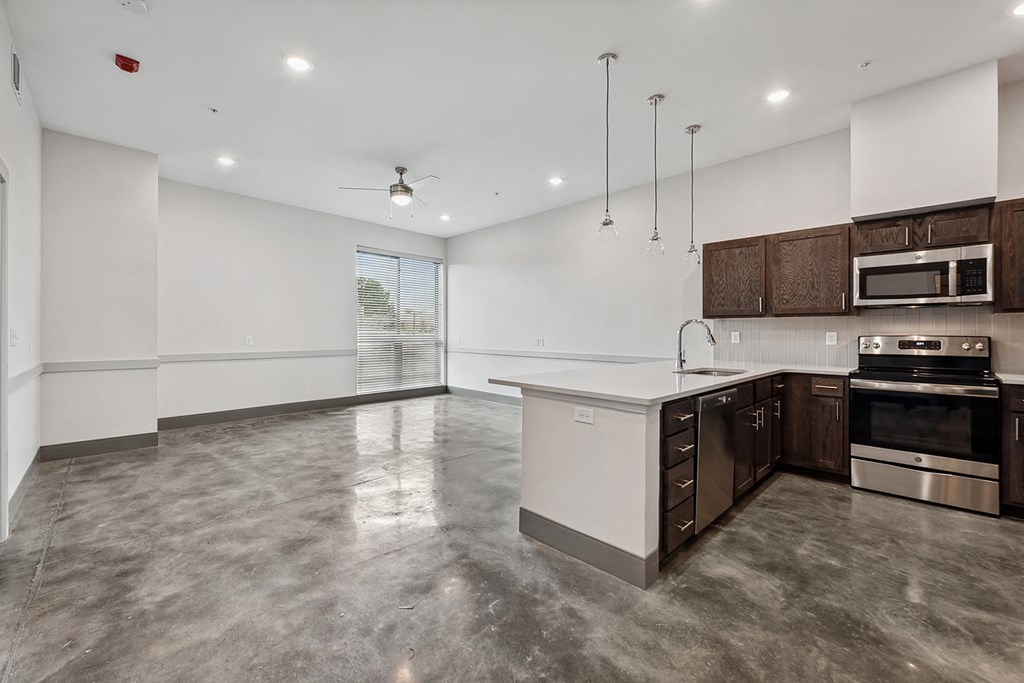 an empty kitchen and living room with white walls and wood cabinets