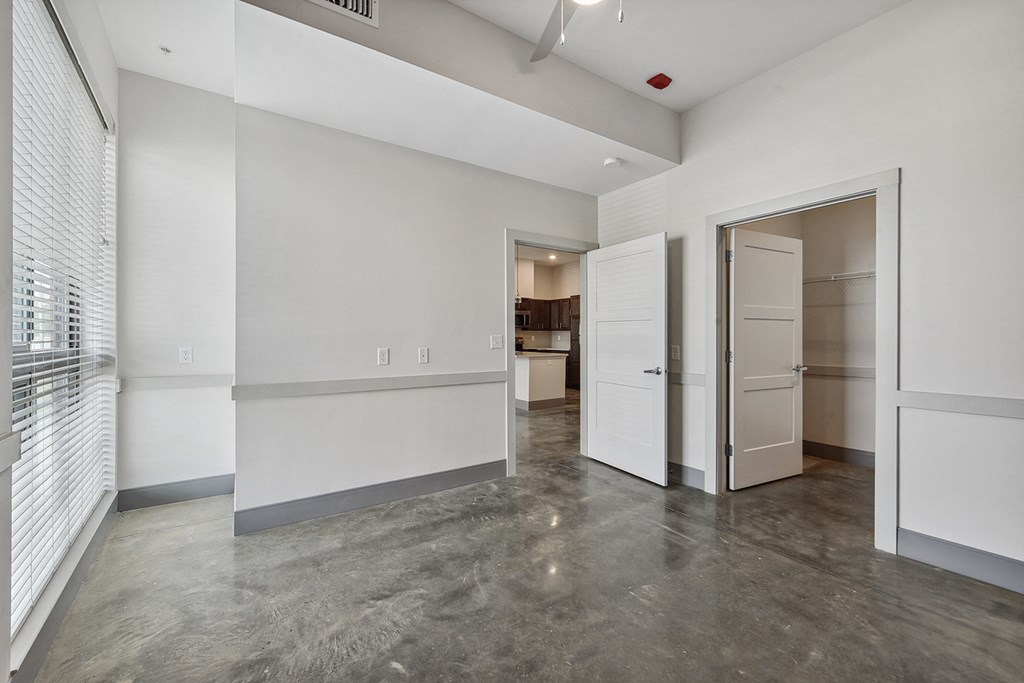 a living room with white walls and a door to a kitchen