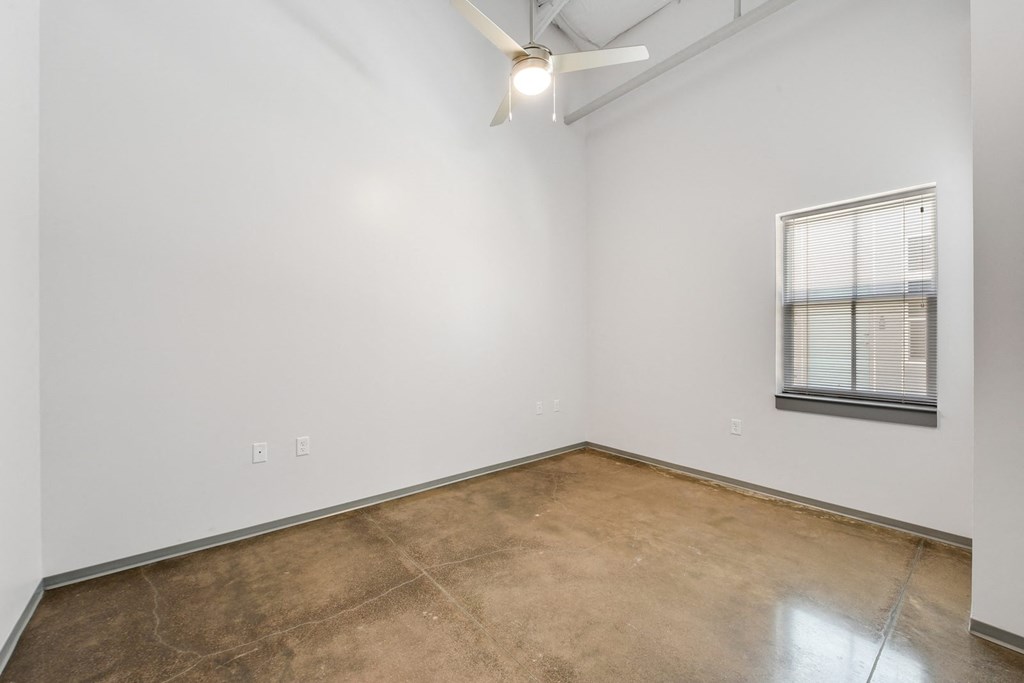an empty room with a window and a ceiling fan