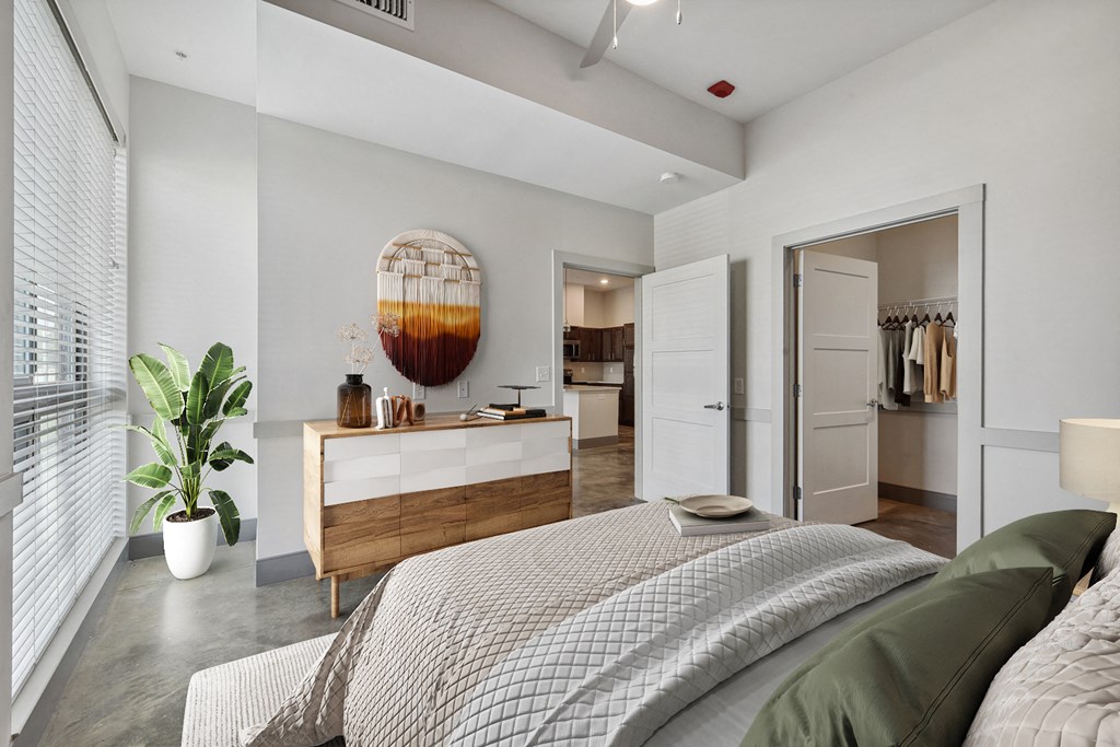 a bedroom with a bed and a dresser and a bathroom