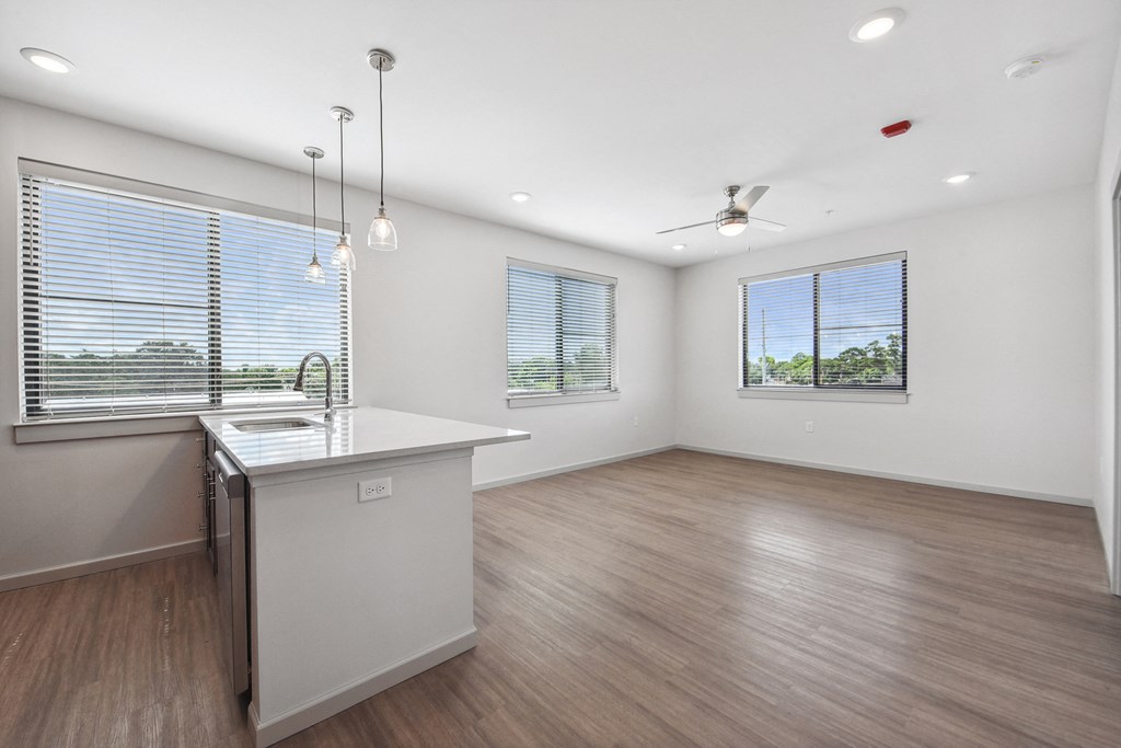 the living room and kitchen of a new home with white walls and wood flooring