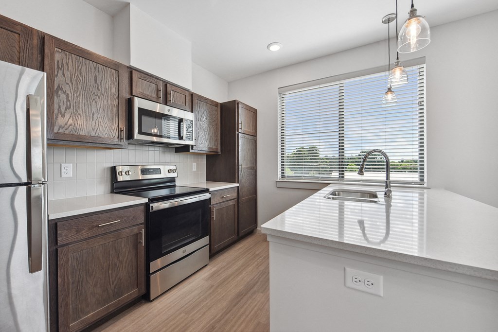 a kitchen with a large window and wooden cabinets and a sink