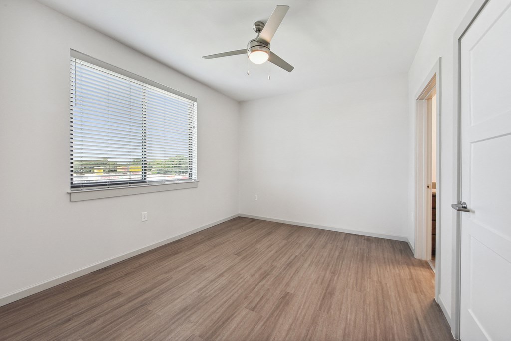 an empty living room with a ceiling fan and a window