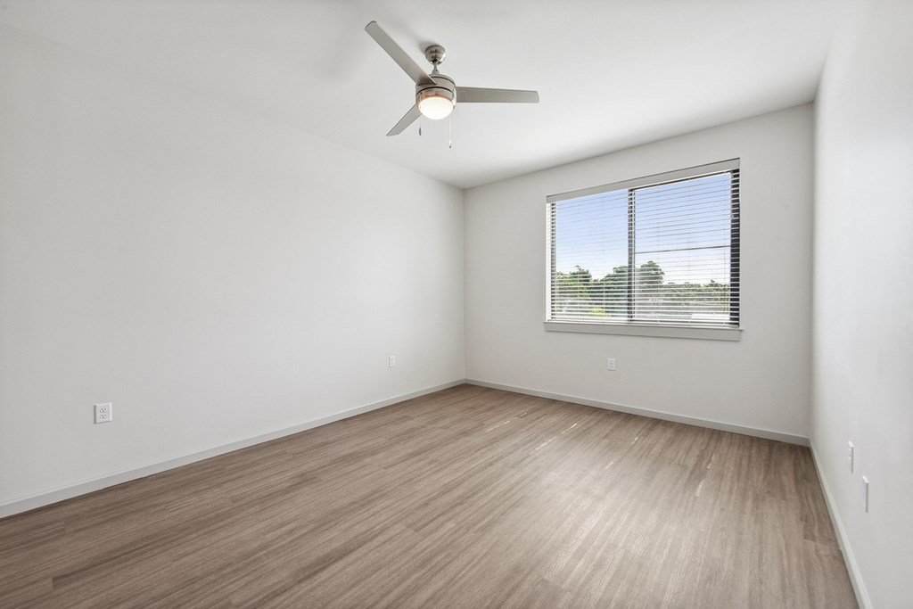 an empty room with a ceiling fan and a window