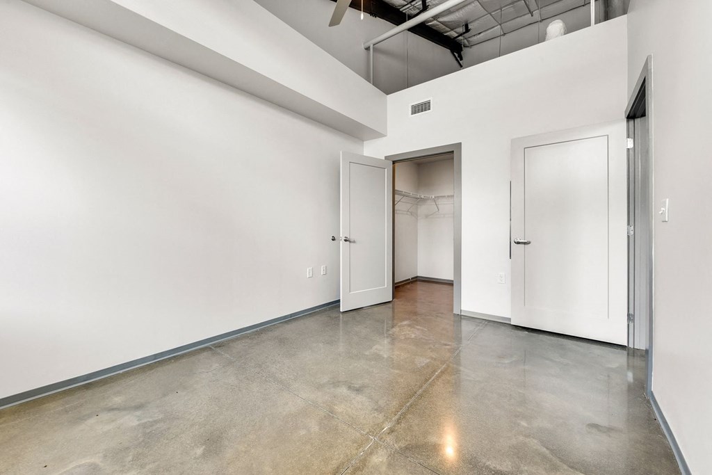 an empty room with white walls and doors and a polished concrete floor