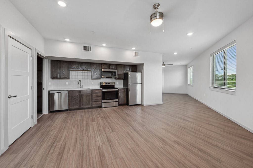 the living room and kitchen in a new home with white walls and wood flooring