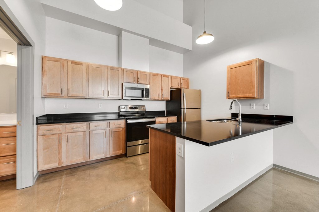 a kitchen with wooden cabinets and a black counter top