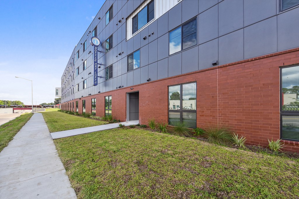 the side of a building with a sidewalk and grass