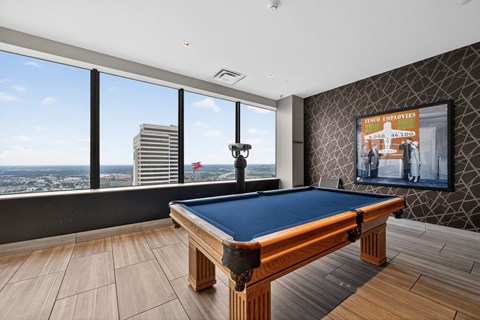 A pool table in a room with a view of the city.