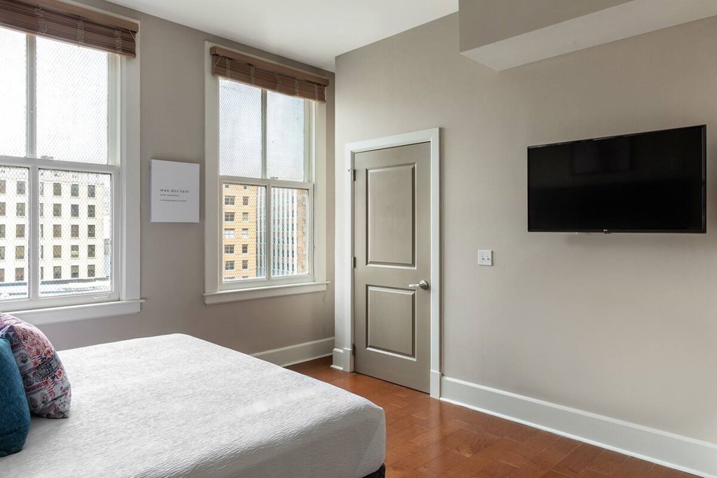 A bedroom with a bed, a door, and a window.