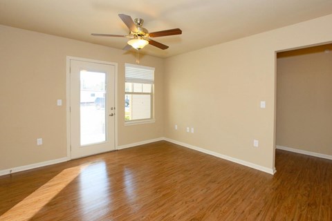 A room with a ceiling fan and wooden flooring.