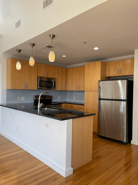 A kitchen with wooden cabinets and a black counter top.