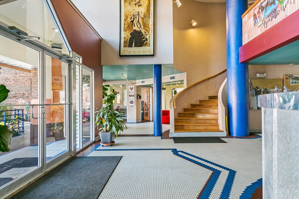 the lobby of a building with a staircase and glass doors