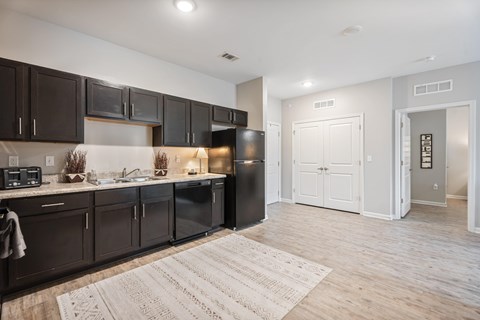 A kitchen with dark brown cabinets and a black refrigerator.
