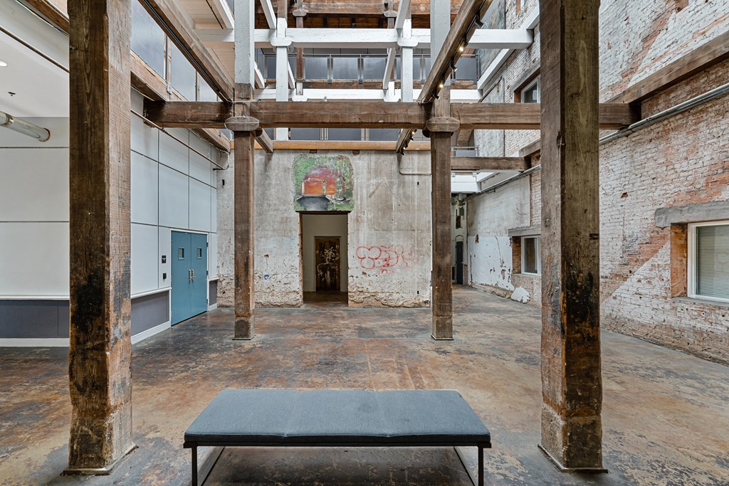 a large room with a bench and a painting on the wall