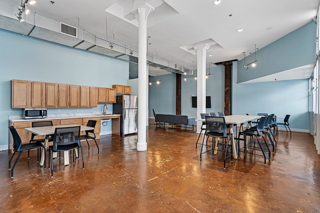 a large room with tables and chairs and a kitchen