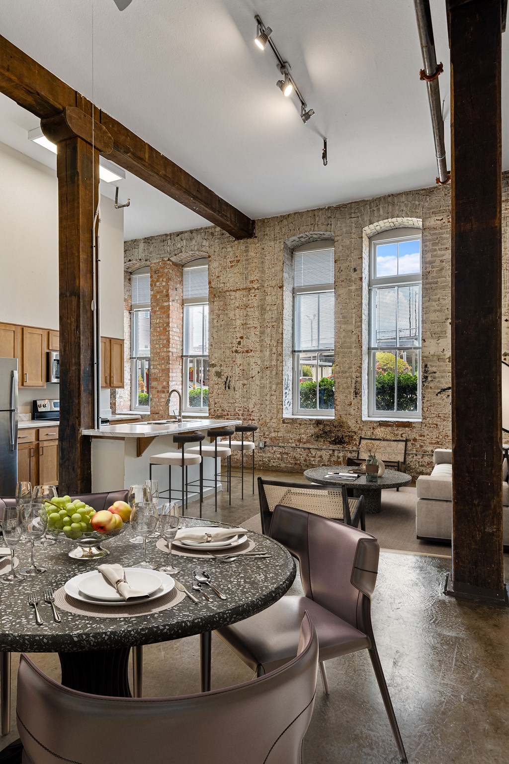 a dining room with a table and chairs and a kitchen with an exposed brick wall