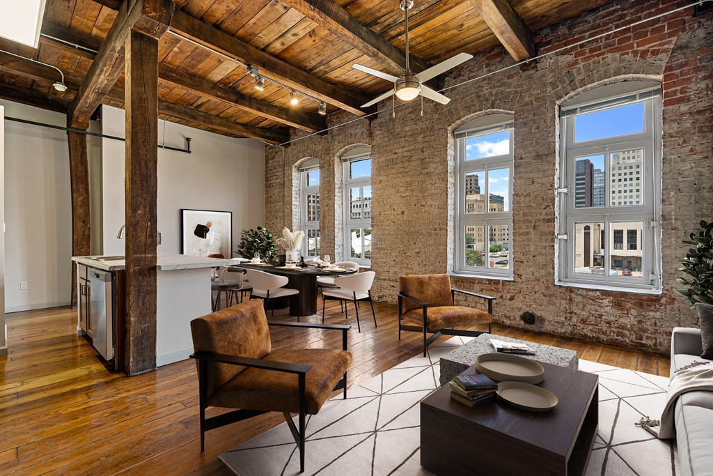 an open living room with exposed brick walls and a kitchen with a table and chairs