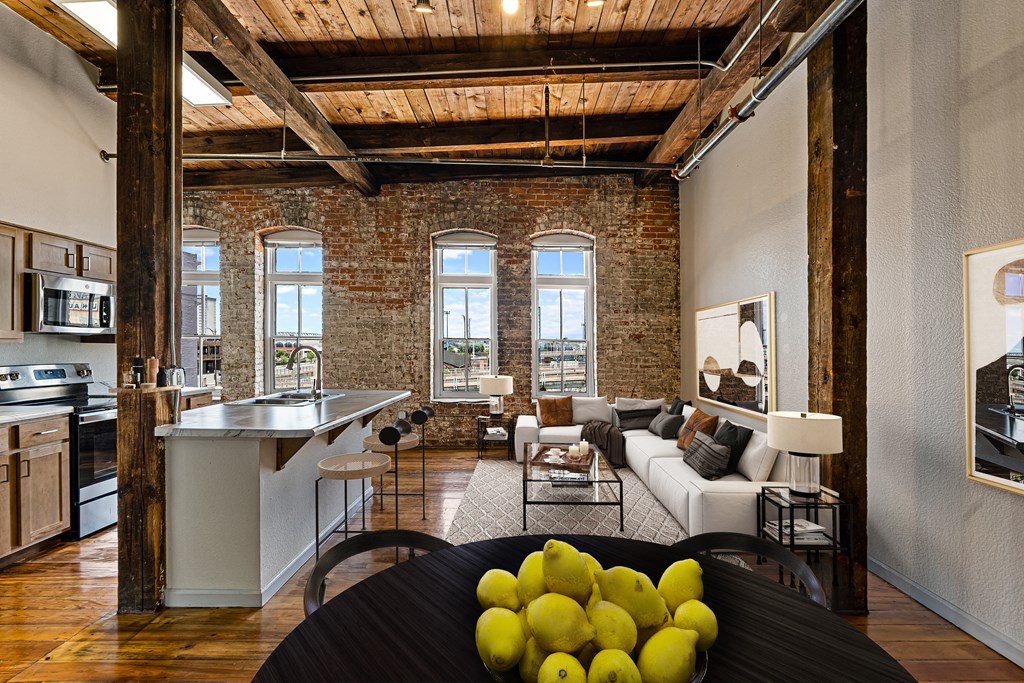 an open living room with a kitchen and exposed brick walls