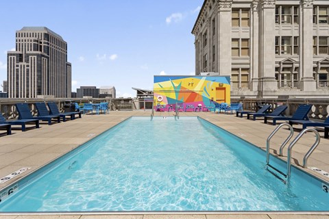 A large outdoor swimming pool with a mural on the wall.