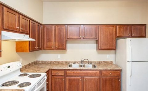 A kitchen with wooden cabinets and a white stove top oven.