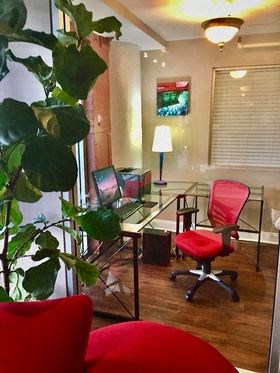 a office with a glass desk and a red chair