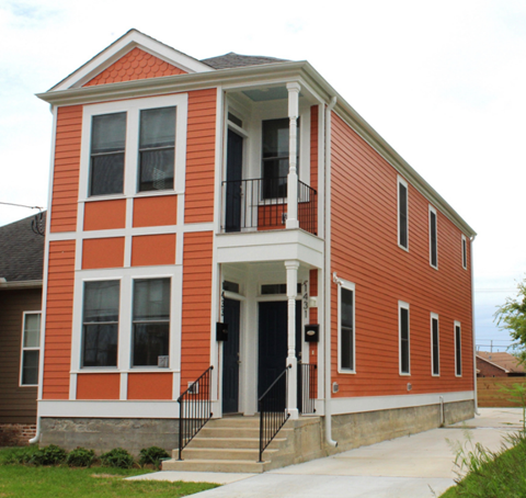 A red and white two story house with a balcony on the second floor.