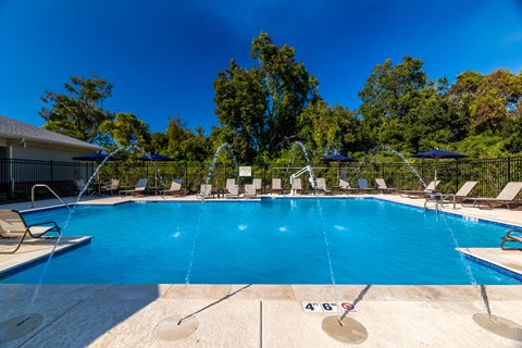 A swimming pool with a blue water and white lounge chairs.