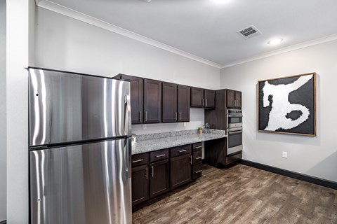 A modern kitchen with a stainless steel refrigerator and wooden floors.