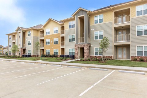 Apartment building with a parking lot in front.