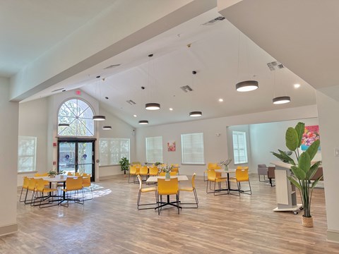 a dining room with yellow chairs and tables and a large window