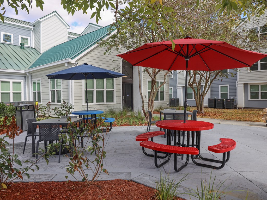 a patio with tables and umbrellas in front of houses